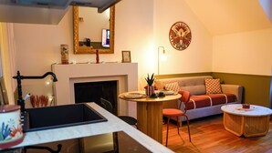 A living room with a fireplace, a sofa, a round table, and a wall-mounted mirror. - La Casa de Miguel - Elegant cocoon 2 steps from the Palais des Papes (Avignon)