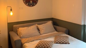 A bedroom with a bed, pillows, a wall clock, and a floor lamp. - La Casa de Miguel - Elegant cocoon 2 steps from the Palais des Papes (Avignon)