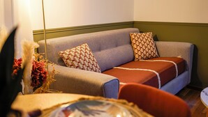 A living room with a sofa, two patterned pillows, a red chair, and a table with a decorative plate. - La Casa de Miguel - Elegant cocoon 2 steps from the Palais des Papes (Avignon)
