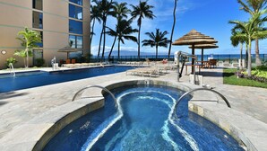 A swimming pool with lounge chairs and palm trees, overlooking a body of water. - ~MAHANA 505~Ocean Front Condo with A/C & Beautiful Island Views in Kaanapali (Lahaina)