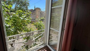A room with a window overlooking a garden, a wooden bench, and a view of a building with a spire. - La demeure aux Lilas a large stone mansion (Cirey-sur-Blaise)