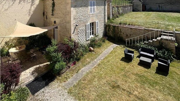 A stone building with a tiled roof, a covered patio, and a grassy yard with outdoor seating. - La demeure aux Lilas a large stone mansion (Cirey-sur-Blaise)