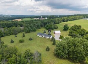 An aerial view of a rural property with a large house, a barn, and surrounding greenery.