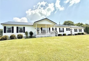 A two-story mobile home with a covered porch and a well-maintained lawn.