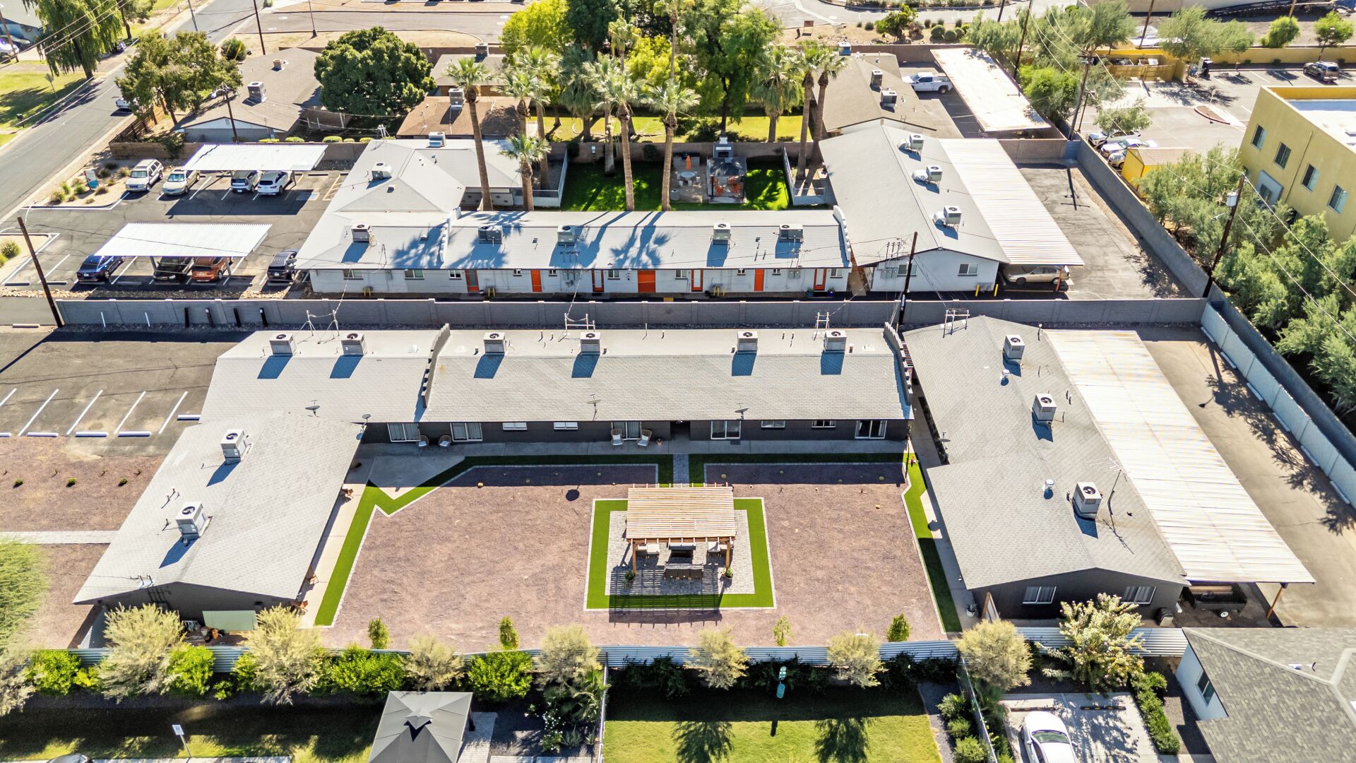 An aerial view of a large building with multiple parking lots, a central courtyard with seating, and surrounding greenery.