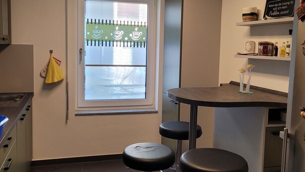 A modern kitchen with a window, bar stools, and a refrigerator. - Modern apartment for families with small children. U1 within walking distance (Nürnberg)