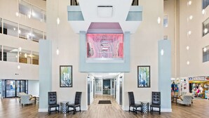 Um hall amplo com uma recepção central, um painel digital grande e vista para a Sea Store.