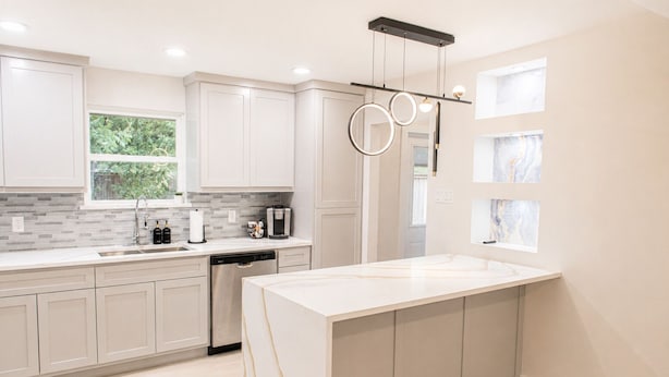 A modern kitchen with white cabinetry, a large island, a coffee machine, and a hanging light fixture. - Modern Dallas Retreat • Golf • Speakeasy• Fire Pit (Dallas)