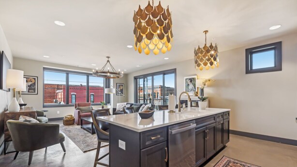 Cocina moderna con una isla central, armarios oscuros e iluminación colgante.