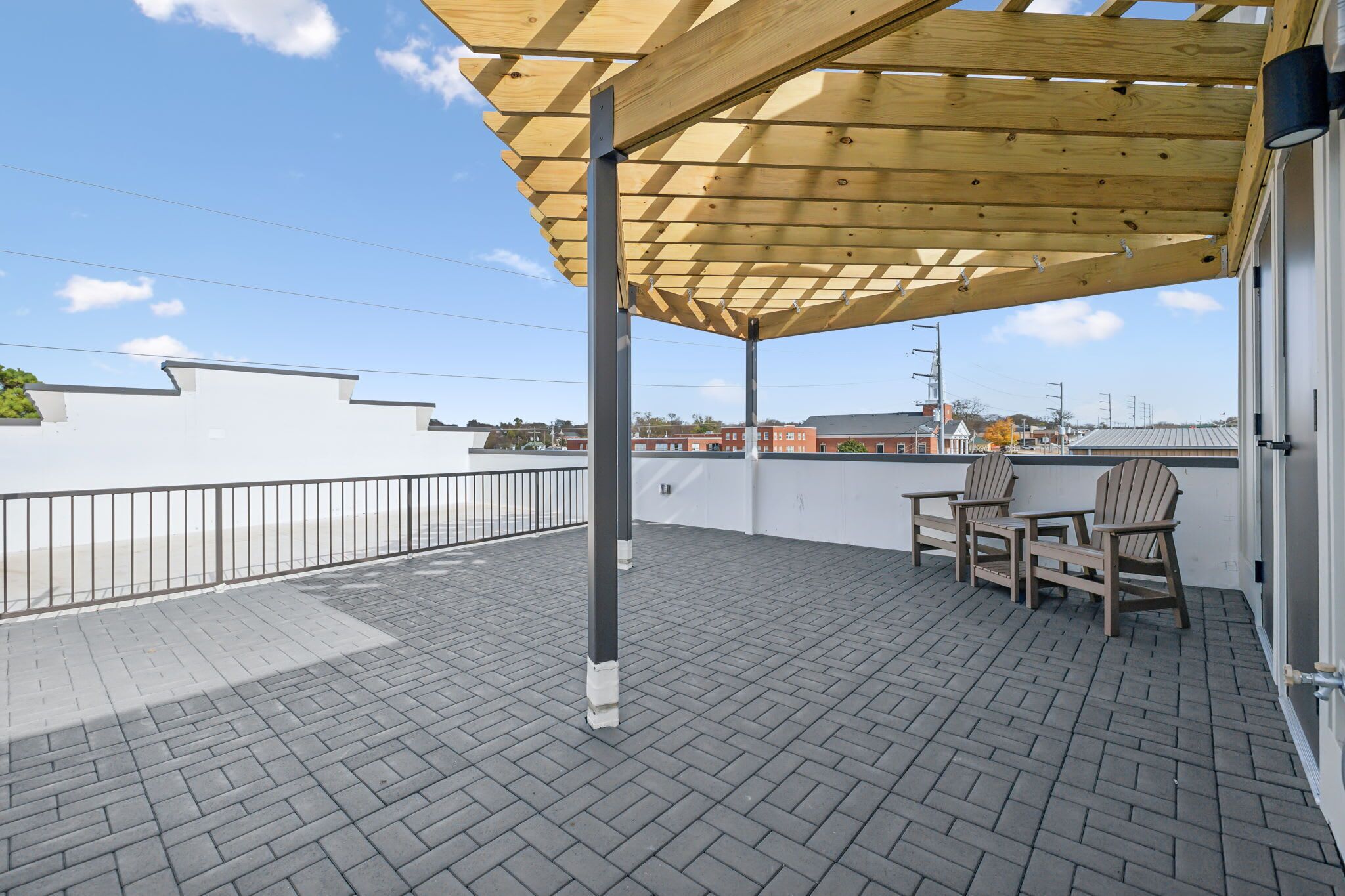 Una terrazza sul tetto con una pergola in legno, due sedie e un tavolo.