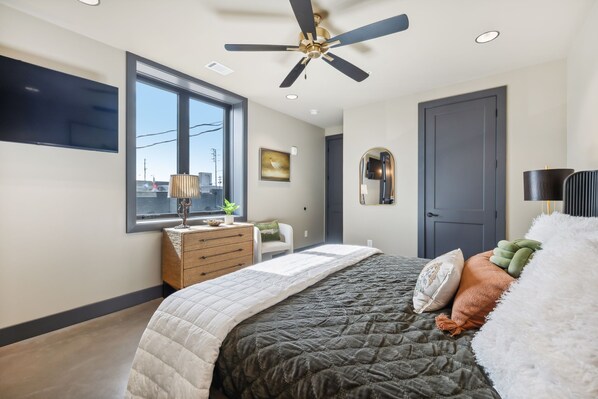 A bedroom with a bed, dresser, window, ceiling fan, and a door. - Modern 2BR : Historic Lebanon • Sleeps 4 (Lebanon)