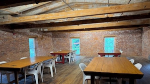 A rustic room with exposed wooden beams, brick walls, and large windows.
