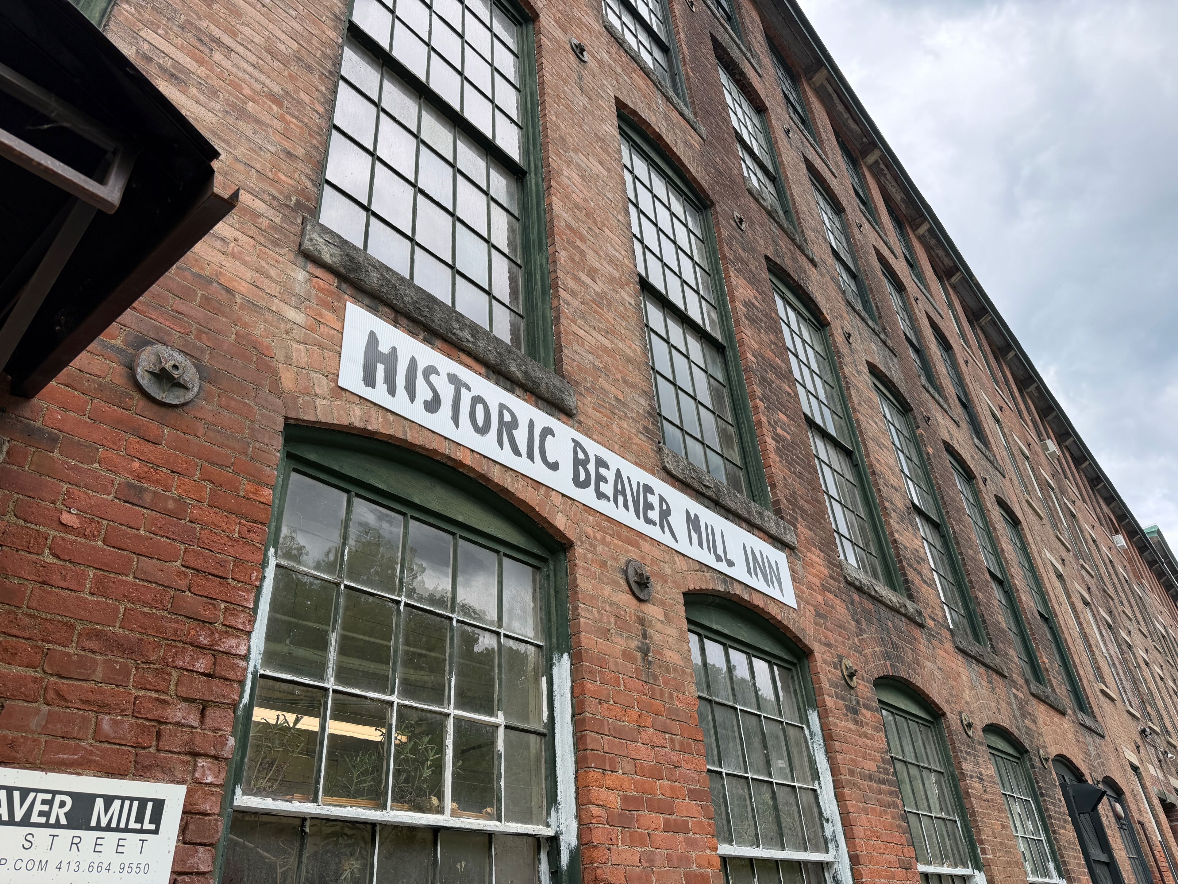 A historic building with a sign reading 'Historic Beaver Mill Inn' and a street sign below it.