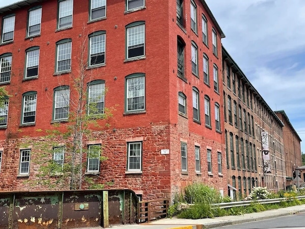 Un edificio de varios pisos de ladrillo rojo con múltiples ventanas y una puerta visible.