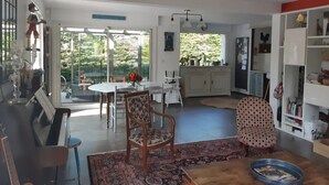 Ein geräumiges Wohnzimmer mit einem Klavier, einem Essbereich und einer Küche mit großem Fenster.