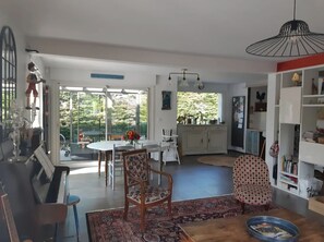 Ein geräumiges Wohnzimmer mit einem Klavier, einem Essbereich und einer Küche mit großem Fenster.