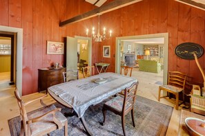 Ein Zimmer mit Holzwänden, einem Esstisch, Stühlen, einer Kandelaber und einem Kamin.