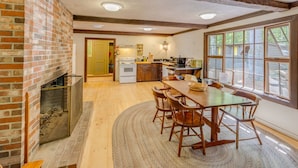 A spacious kitchen with a brick wall, wooden ceiling beams, and a large window. - Squam Lake House - Lakeside With Private Dock and Float (Holderness)
