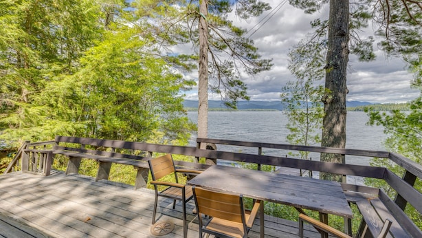 A wooden deck with a table and chairs overlooking a lake. - Squam Lake House - Lakeside With Private Dock and Float (Holderness)