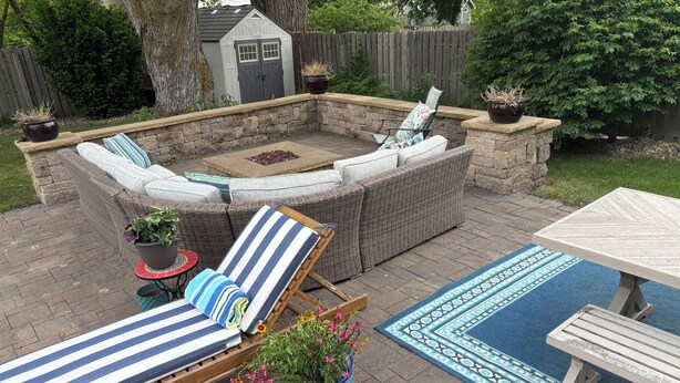 Une terrasse avec un foyer en pierre, des fauteuils et une table.