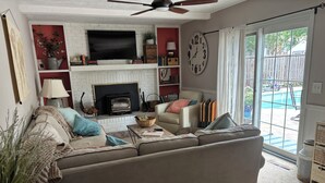 Un salon avec un canapé, une cheminée, un téléviseur et une horloge au mur.