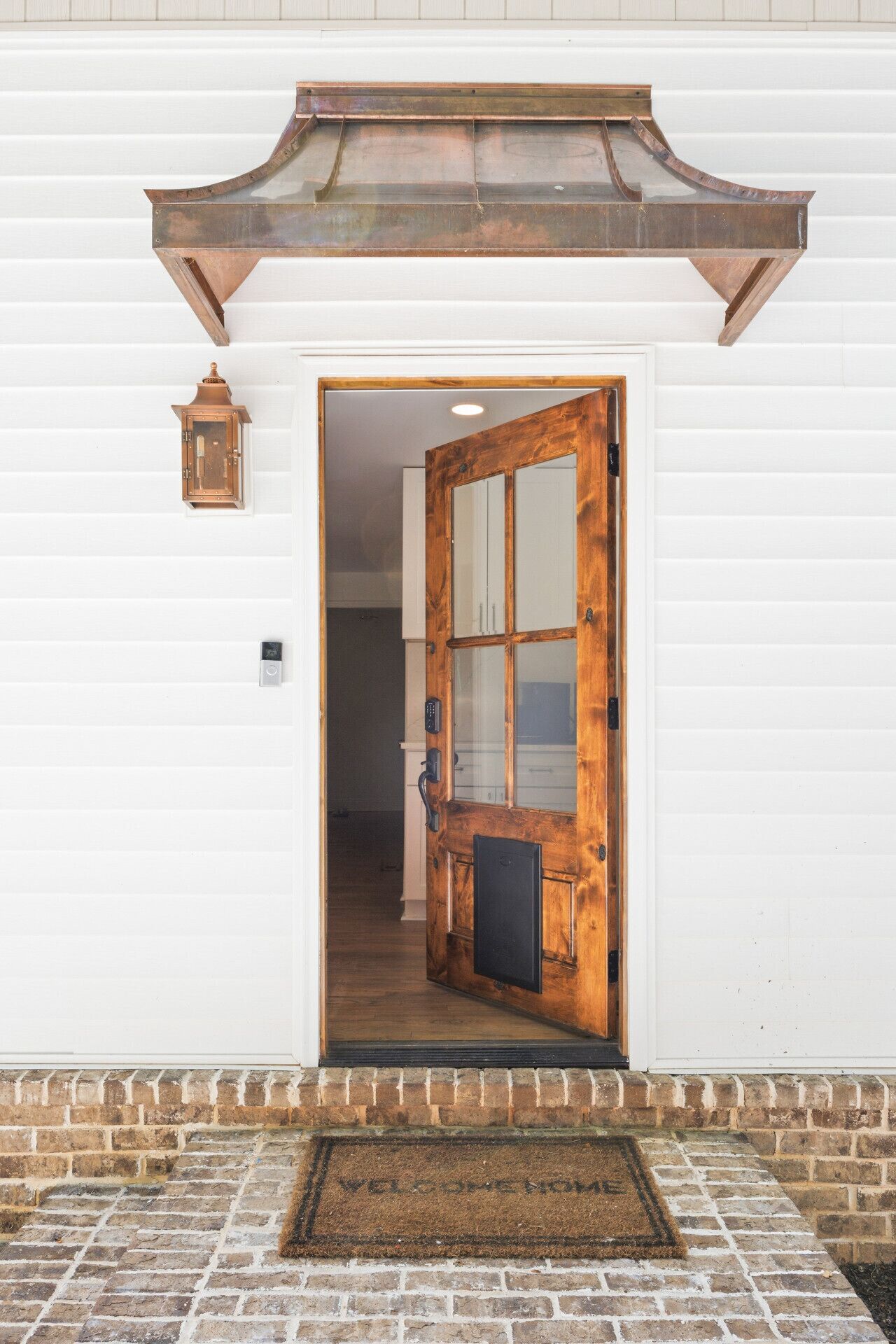 Une porte en bois avec un panneau de verre, une lanterne en métal et des fondations en briques.