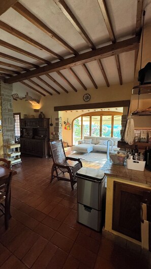 A spacious living area with a high ceiling, a stone fireplace, a sofa, and a dining table. - Magical Umbrian Villa with pool! (MONTECASTRILLI)