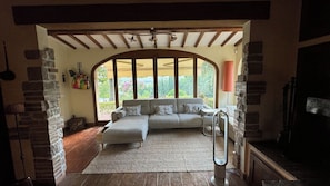 A cozy living room with a sectional sofa, a fireplace, and a view through a large arched window.