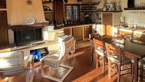 Una cocina amplia con vigas de madera, chimenea y comedor con sillas modernas.