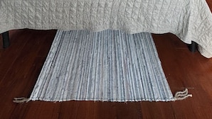 Un dormitorio con una cama grande, vigas de madera en el techo, una ventana con cortinas y una mesita de noche con una lámpara.