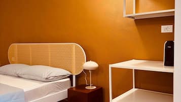Una camera da letto con un letto, un comodino, una lampada e una libreria bianca.