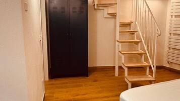 Une chambre à coucher avec un lit, un escalier en bois, une armoire et un tapis à motifs.