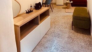 Un espace de vie compact comprenant un coin cuisine, un coin repas et un coin salon avec un canapé rouge et un pouf vert.