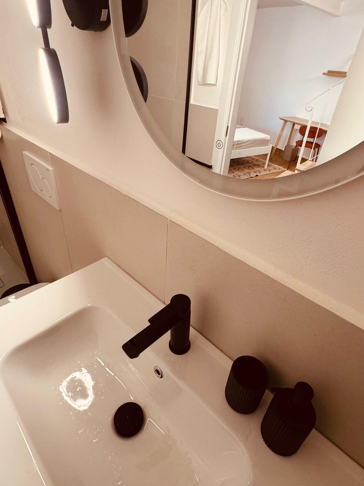 Un bagno con un lavandino bianco, uno specchio e un porta asciugamani.