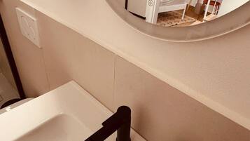 Un bagno con un lavandino bianco, uno specchio e un porta asciugamani.