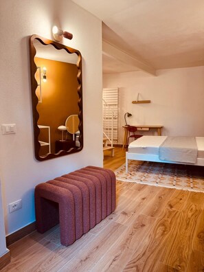 Ein Schlafzimmer mit einem großen Spiegel, einer Bank, einem Bett, einem Schreibtisch und einem Stuhl.