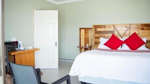 Una habitación con una cama, un escritorio, una silla, un cabecero de madera y una puerta blanca.