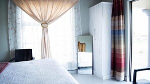 Habitación de hotel con cama, armario, silla y vistas al exterior.