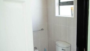 Un baño pequeño y limpio con inodoro, ventana y barra para toallas.