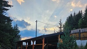 A rustic cabin with a wooden deck, surrounded by dense greenery and a stone wall. - Srce Kamene Gore – peaceful mountain retreat with spa & nature. (Kamena Gora)