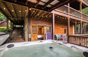 Eine Blockhütte mit Whirlpool, Holzterrasse und überdachter Außenbereich.