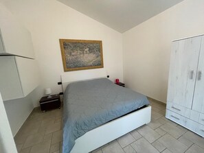 Une chambre à coucher avec un lit, une table de chevet, une lampe, une armoire et un tableau au mur.