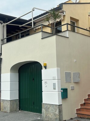 Ein Gebäude mit grüner Tür, einer Satellitenschüssel und einer Treppe, die zu einem Balkon führt.