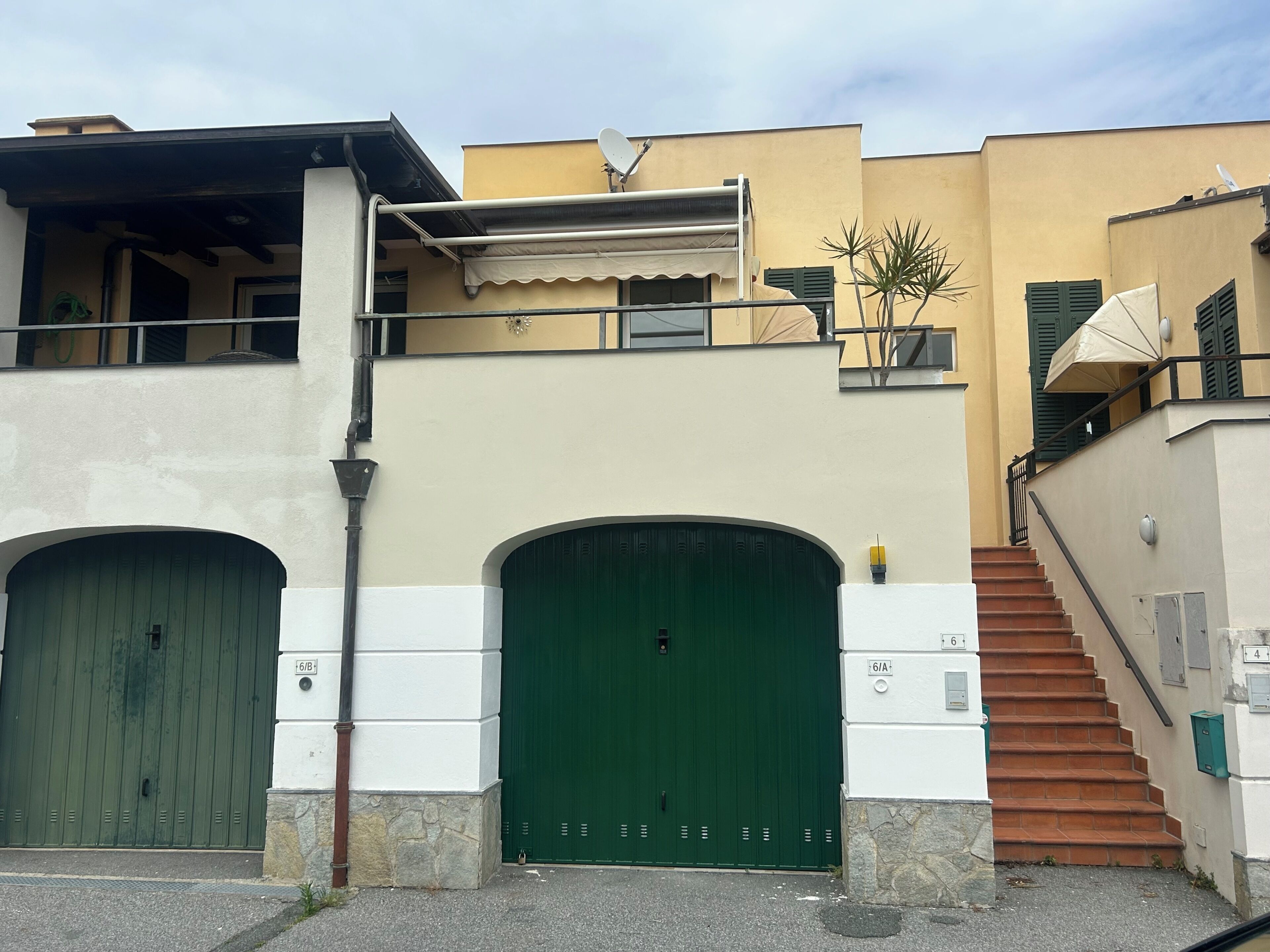 Un bâtiment doté de deux portes vertes à double battant, d’un escalier et d’une antenne parabolique.