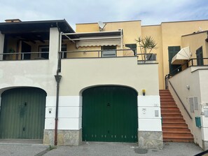 Un bâtiment doté de deux portes vertes à double battant, d’un escalier et d’une antenne parabolique.