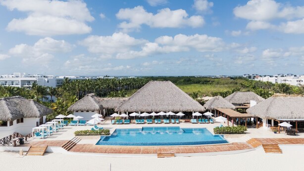 Ein Resort mit Schwimmbad, strohgedeckten Gebäuden und Blick auf die Küste.