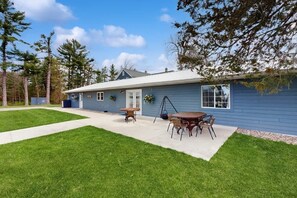 Ein Bungalow mit überdachter Terrasse, Rasenfläche und kleinem Garten.