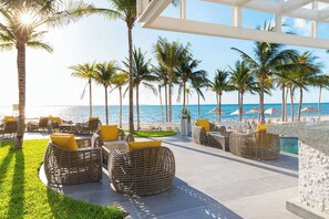 A beachside lounge with wicker furniture and a view of the ocean.