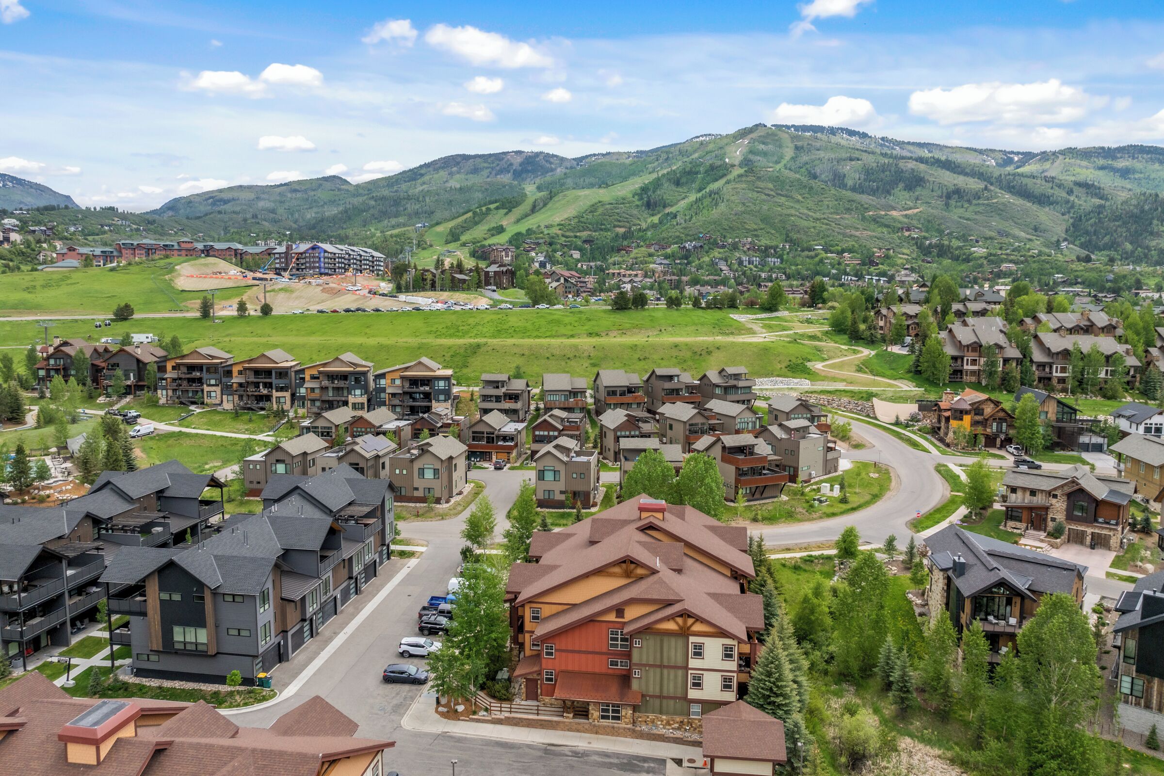 Un quartier résidentiel avec des maisons modernes, une route sinueuse et un paysage montagneux en arrière-plan.