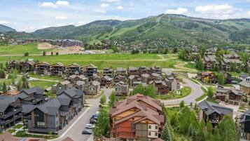 Un quartier résidentiel avec des maisons modernes, une route sinueuse et un paysage montagneux en arrière-plan.